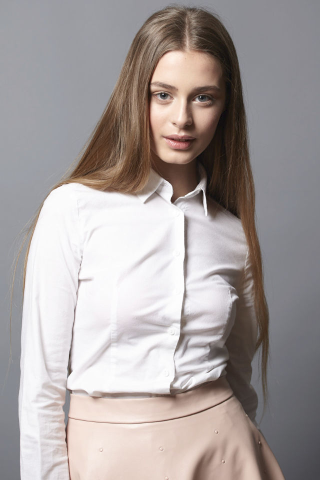 Sasha studio portrait. White long sleeve shirt, confident gaze.
